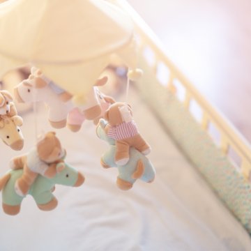 Overhead side shot of baby crib with toys above the mattress